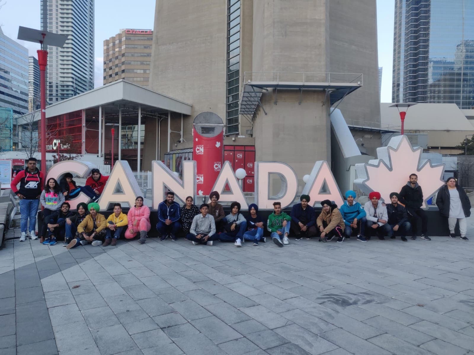 Students seated at the CANADA letters below the CN Tower in Toronto